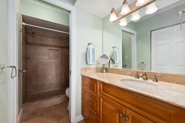 bathroom with a tile shower, vanity, and toilet