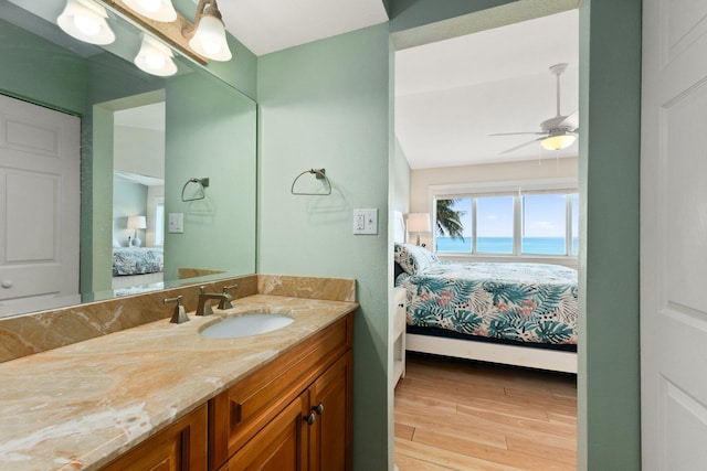 bathroom with a water view, ceiling fan, hardwood / wood-style flooring, and vanity