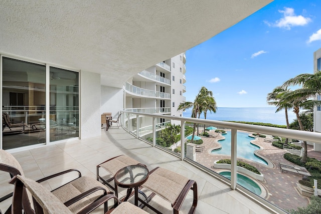 balcony featuring a community hot tub, a patio, and a water view