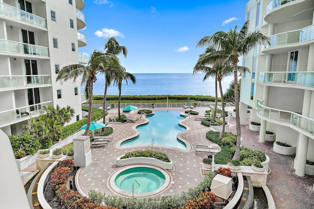 view of swimming pool featuring a community hot tub, a water view, and a patio area