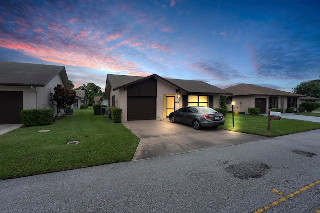 ranch-style house with cooling unit, a yard, and a garage