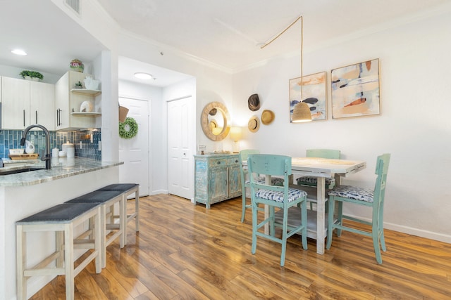 dining room featuring crown molding, sink, and dark hardwood / wood-style flooring