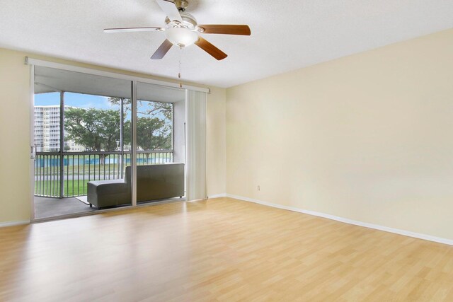 spare room with ceiling fan, a textured ceiling, floor to ceiling windows, and light hardwood / wood-style floors