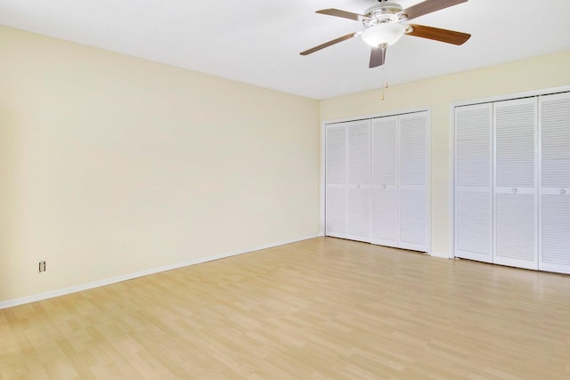 unfurnished bedroom featuring light hardwood / wood-style flooring, two closets, and ceiling fan