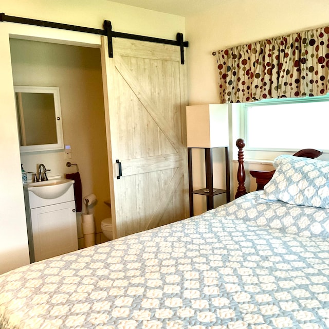 bedroom featuring sink, a barn door, and connected bathroom