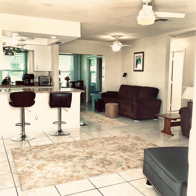 kitchen featuring light tile patterned flooring, plenty of natural light, white cabinets, and a kitchen bar