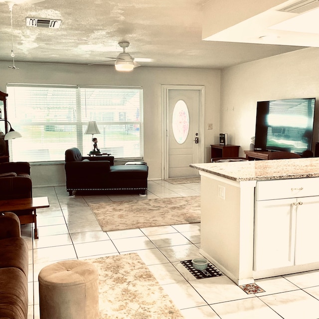 interior space with light stone counters, white cabinets, ceiling fan, light tile patterned floors, and a textured ceiling