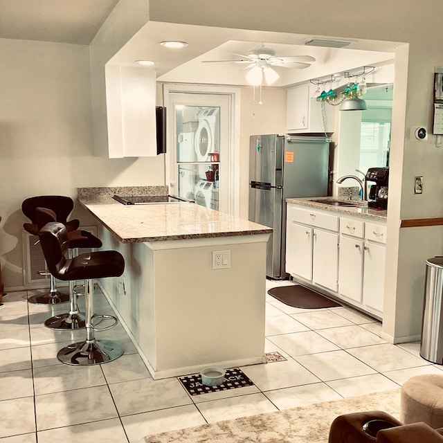 kitchen featuring light stone counters, white cabinets, sink, kitchen peninsula, and a breakfast bar area