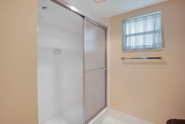 bathroom with a shower with door and tile patterned floors