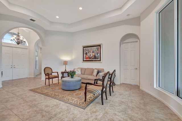 9772 Via Grandezza W, Wellington, FL 33411 - living area featuring light tile patterned floors, arched walkways, an inviting chandelier, a tray ceiling, and visible vents