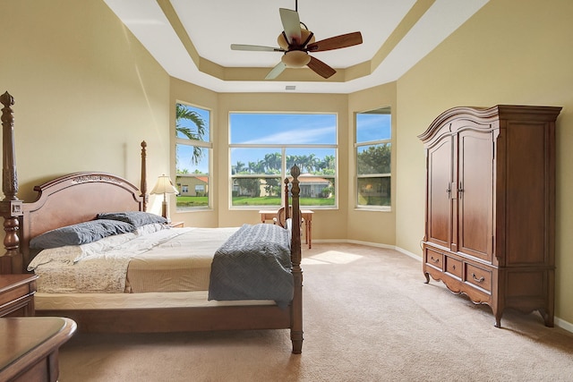 carpeted bedroom featuring ceiling fan and a raised ceiling