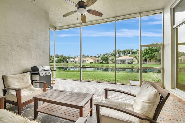 sunroom / solarium featuring ceiling fan and a water view