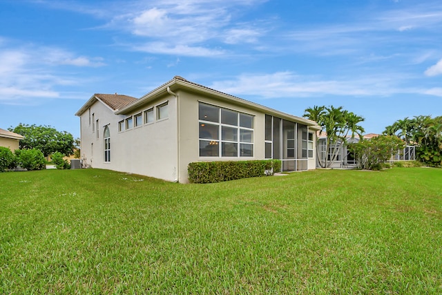 view of side of property featuring a sunroom, cooling unit, and a yard