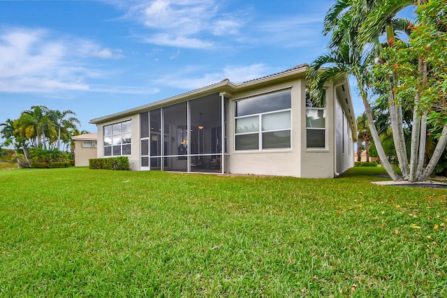 9772 Via Grandezza W, Wellington, FL 33411 - back of house featuring a sunroom, stucco siding, and a lawn