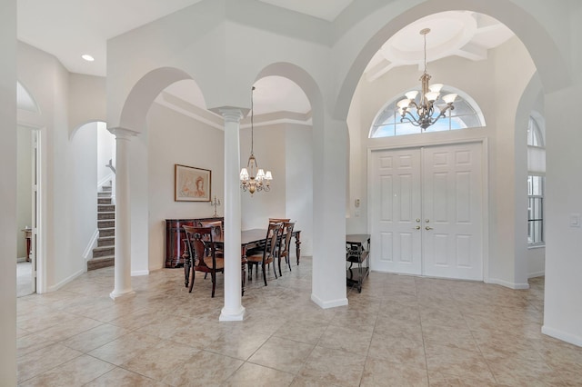 foyer entrance with an inviting chandelier, a high ceiling, light tile patterned floors, and ornate columns