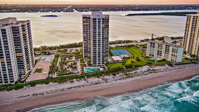 aerial view at dusk with a water view and a view of the beach