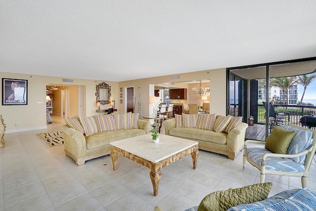 tiled living room with a textured ceiling, an inviting chandelier, and a wall of windows