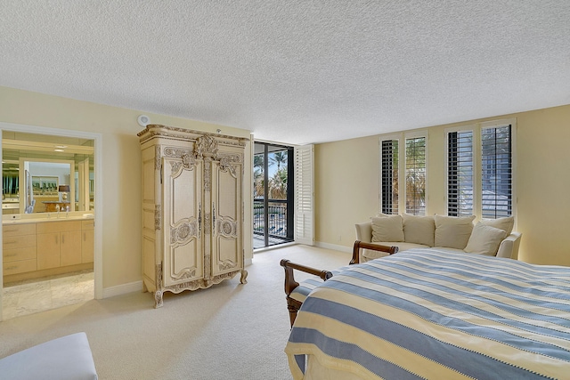 carpeted bedroom featuring ensuite bathroom, access to exterior, and a textured ceiling