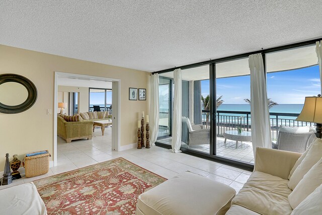 tiled living room featuring floor to ceiling windows, a water view, a textured ceiling, and a chandelier