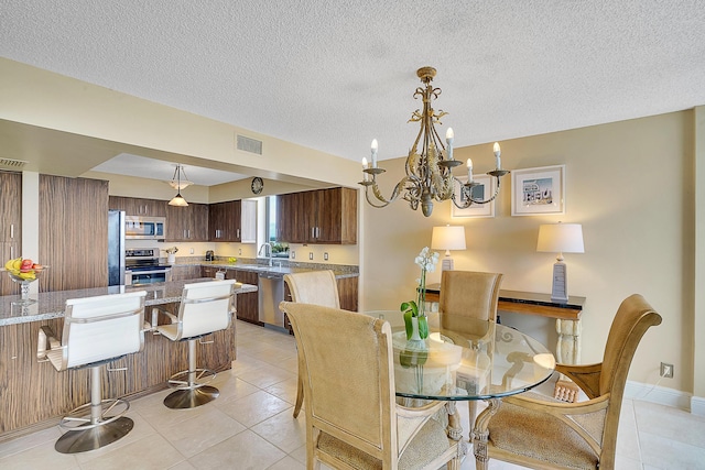 dining area featuring light tile patterned floors, a textured ceiling, sink, and a chandelier