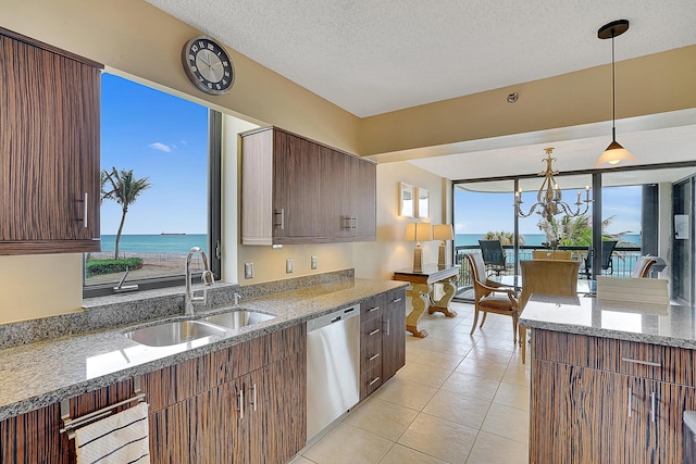 kitchen featuring sink, a water view, decorative light fixtures, dishwasher, and light stone countertops