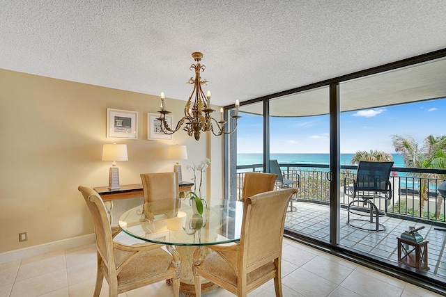 dining space featuring light tile patterned flooring, a chandelier, floor to ceiling windows, a water view, and a textured ceiling