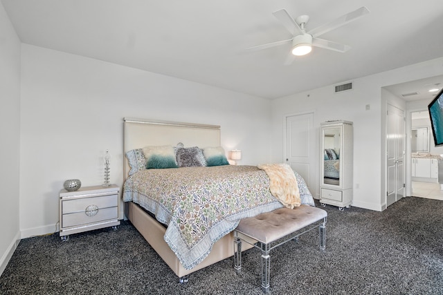 bedroom featuring ceiling fan, ensuite bathroom, and dark colored carpet