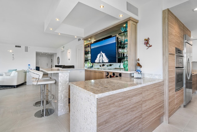 bar with stainless steel refrigerator, light stone countertops, and light tile patterned floors