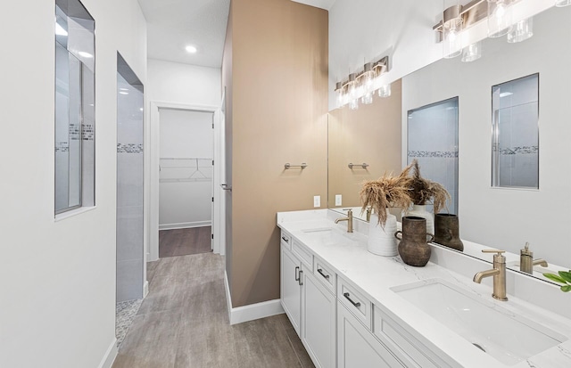 bathroom featuring hardwood / wood-style floors, tiled shower, and vanity