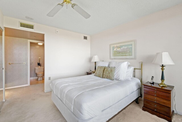 bedroom with connected bathroom, a textured ceiling, light colored carpet, and ceiling fan