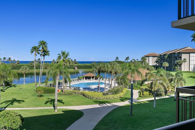 view of community featuring a water view, a swimming pool, and a lawn