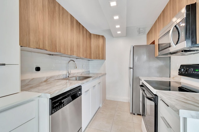 kitchen featuring decorative backsplash, appliances with stainless steel finishes, sink, white cabinets, and light tile patterned flooring