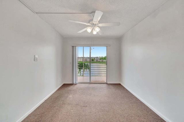 unfurnished room with carpet, ceiling fan, a water view, and a textured ceiling