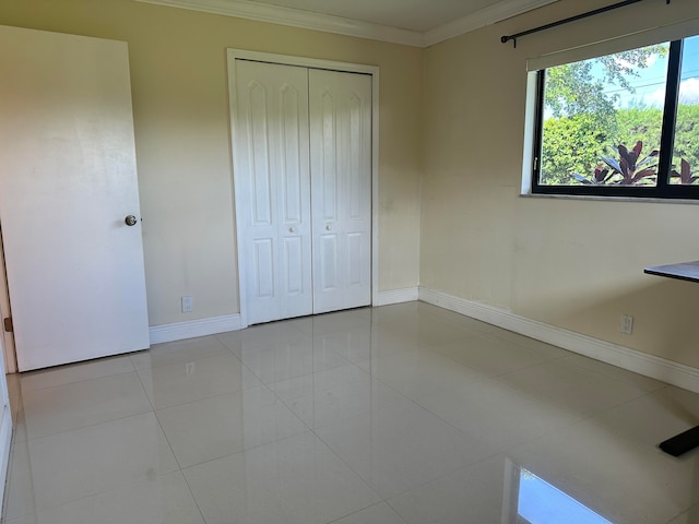 unfurnished bedroom with a closet, crown molding, and light tile patterned floors