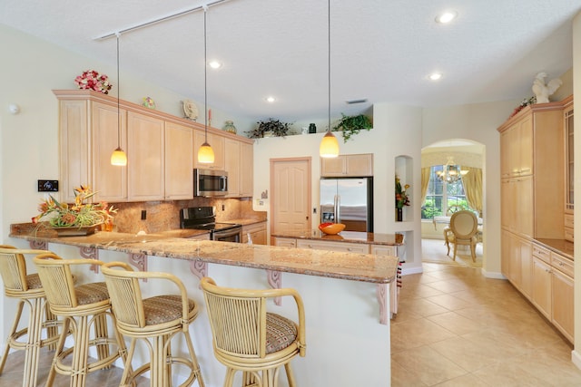 kitchen featuring appliances with stainless steel finishes, kitchen peninsula, an inviting chandelier, and pendant lighting