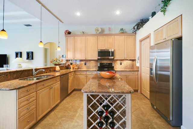 kitchen with light brown cabinets, hanging light fixtures, sink, kitchen peninsula, and appliances with stainless steel finishes