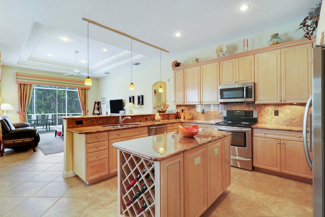 kitchen with pendant lighting, appliances with stainless steel finishes, kitchen peninsula, and a tray ceiling