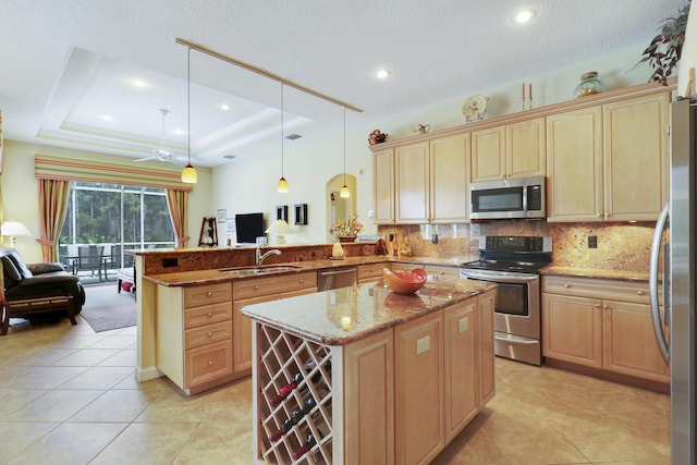 8100 Alister Pl, Port Saint Lucie, FL 34986 - kitchen with appliances with stainless steel finishes, a sink, a peninsula, a tray ceiling, and open floor plan