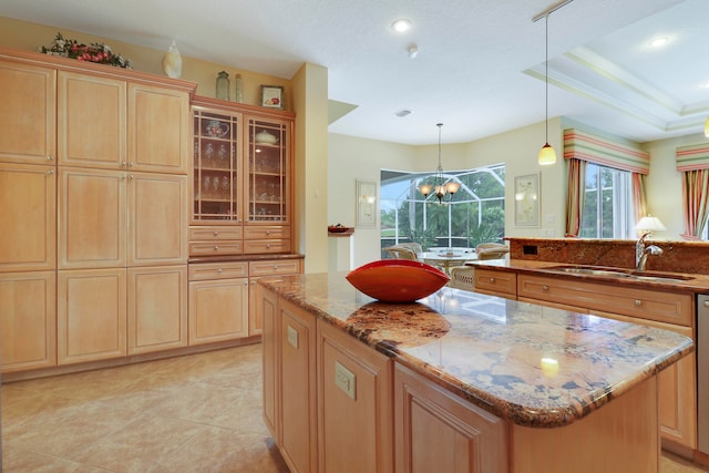 kitchen featuring sink, a kitchen island, decorative light fixtures, an inviting chandelier, and light stone countertops