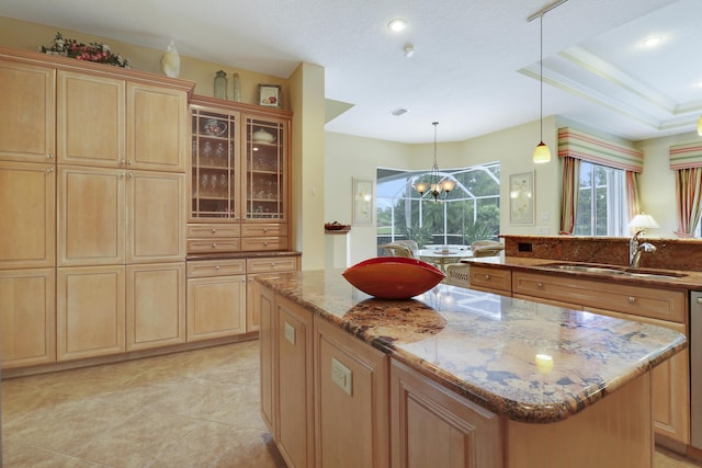 8100 Alister Pl, Port Saint Lucie, FL 34986 - kitchen featuring a sink, light stone countertops, a kitchen island, light brown cabinetry, and glass insert cabinets
