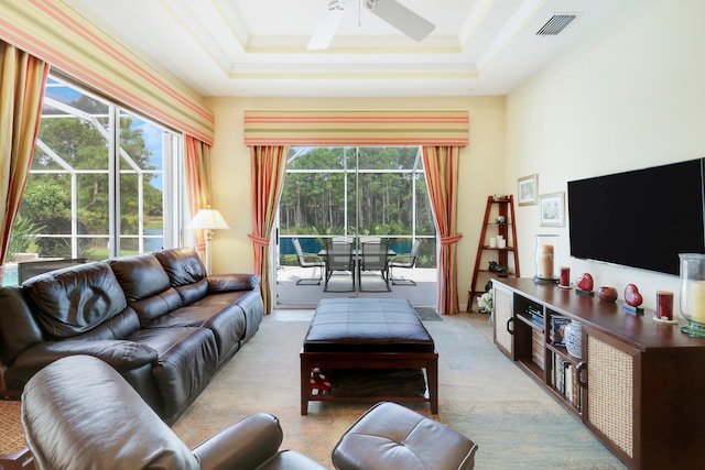 living room with ceiling fan, a tray ceiling, light carpet, and a wealth of natural light