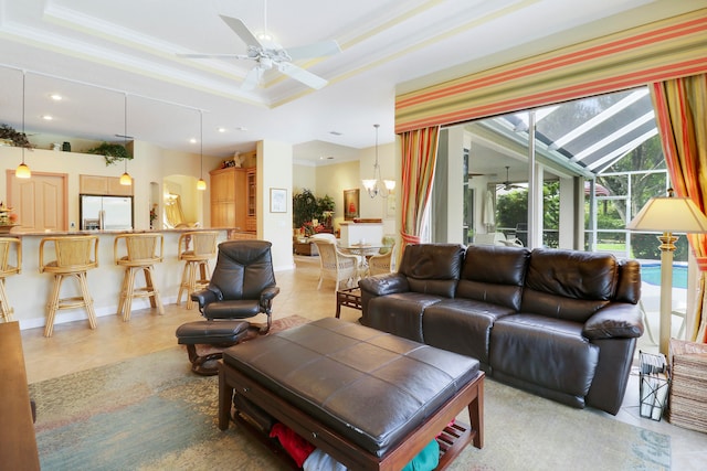 living room with ceiling fan with notable chandelier, crown molding, a raised ceiling, and tile patterned floors