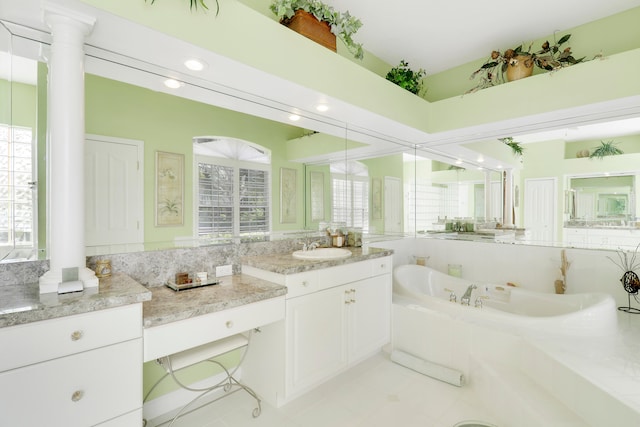 bathroom featuring vanity, tiled bath, and ornate columns