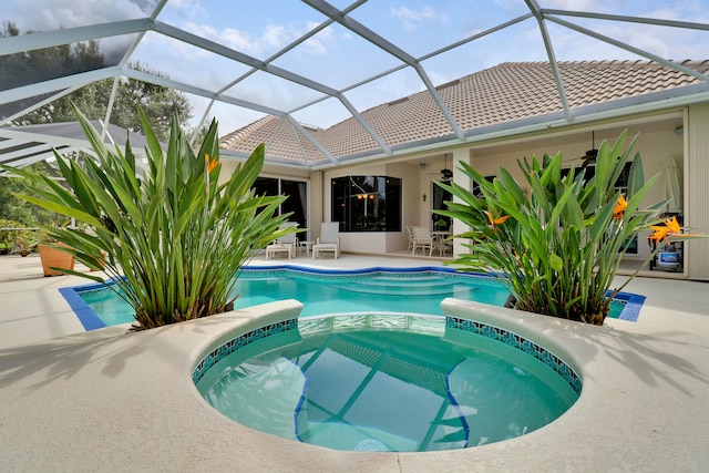 view of swimming pool featuring a patio, glass enclosure, ceiling fan, and an in ground hot tub