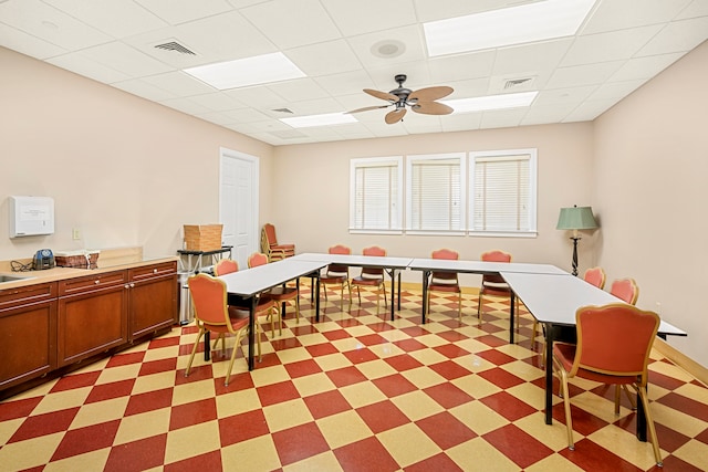 interior space featuring ceiling fan and a drop ceiling