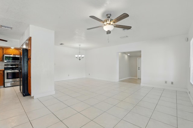 unfurnished room featuring light tile patterned floors, baseboards, visible vents, and ceiling fan with notable chandelier