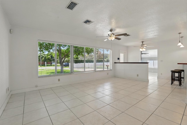 unfurnished room with light tile patterned flooring, a textured ceiling, visible vents, and ceiling fan