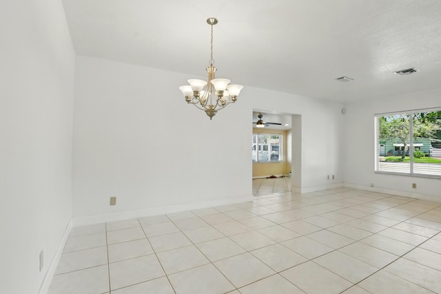empty room featuring visible vents, ceiling fan with notable chandelier, a wealth of natural light, and light tile patterned floors