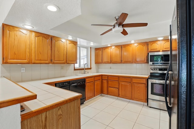 kitchen featuring a sink, tile countertops, black appliances, ceiling fan, and backsplash
