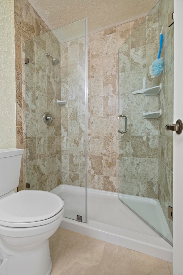 bathroom with a textured ceiling, toilet, walk in shower, and tile patterned floors